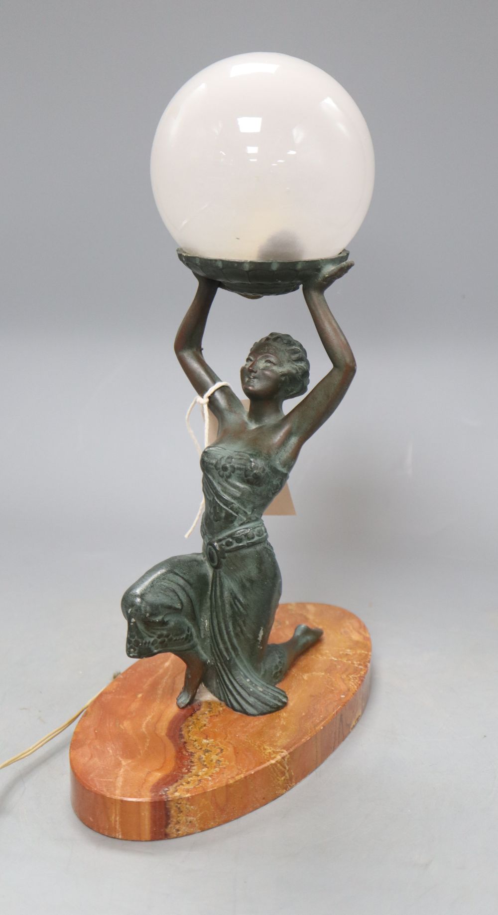 An Art Deco table lamp modelled as bronzed kneeling lady holding a globe, on oval rouge marble base, height 31.5cm